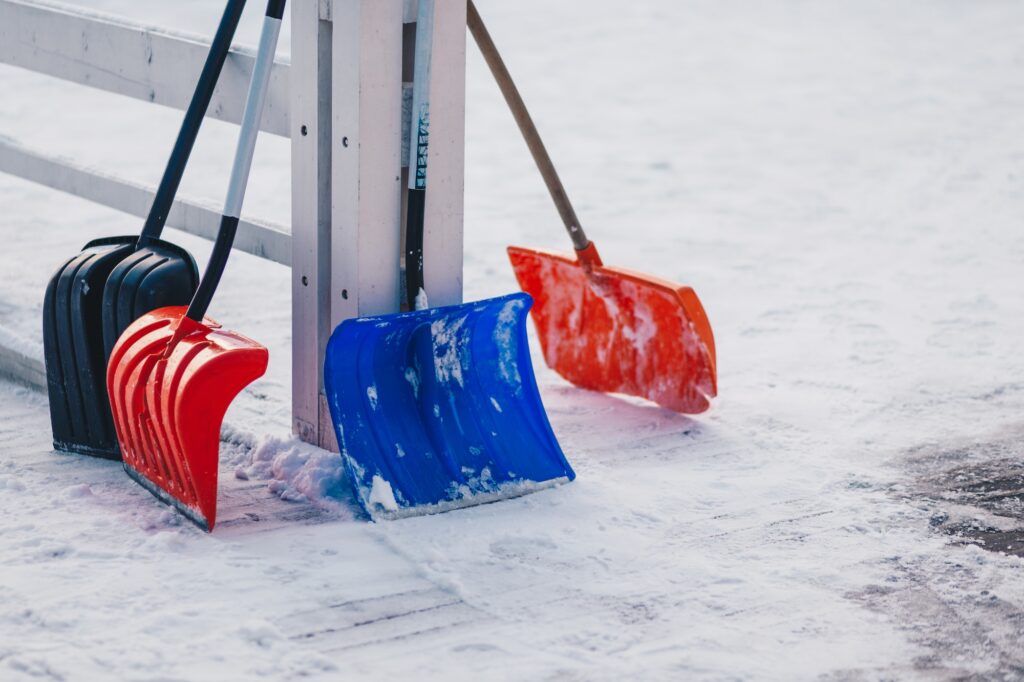 Colourful four plastic shovels stand on snow. Winter time. Shoveling deep snow