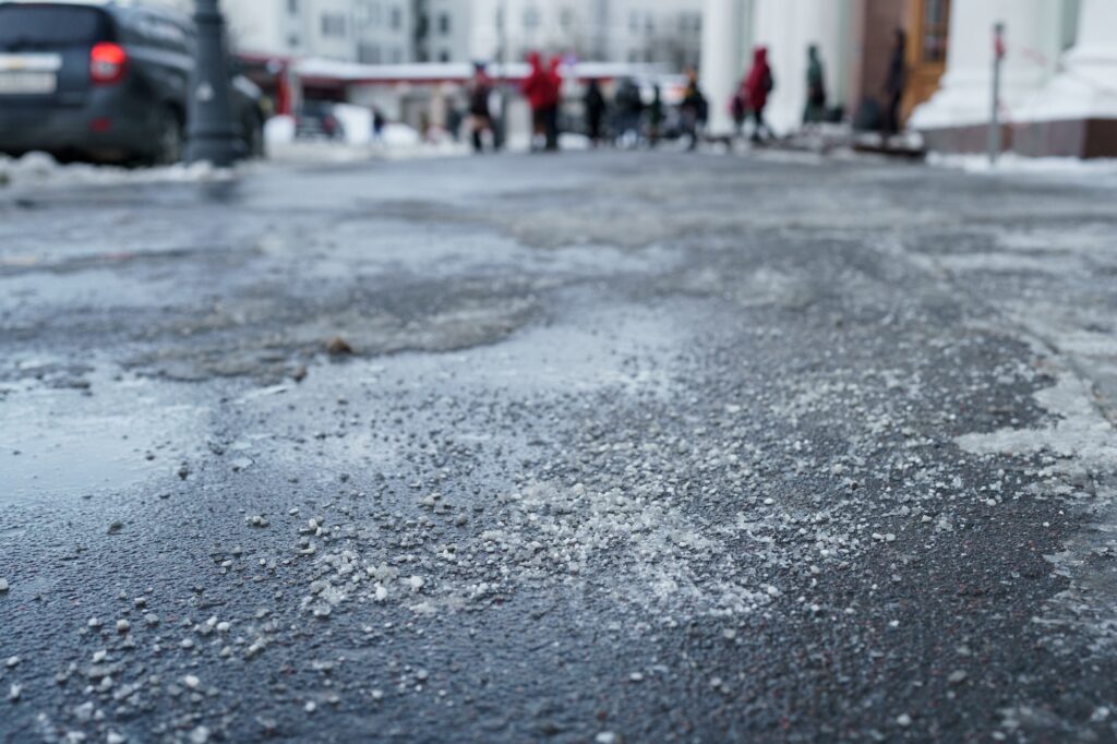De-icing chemical reagent on road in winter time. Pavement is sprinkled with technical salt